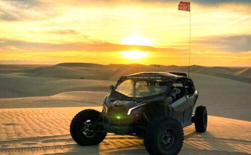 ATV parked in sand dunes with sunset in background